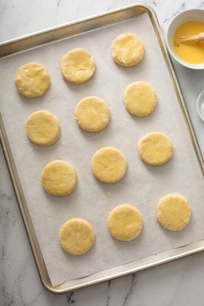 Biscuit dough brushed with egg wash on a sheet pan lined with parchment paper