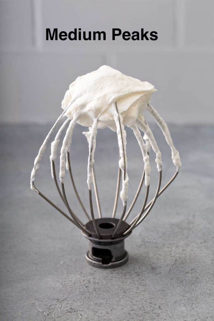 Homemade whipped cream at medium peaks on a whisk attachment