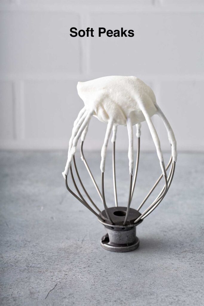 Homemade whipped cream at soft peaks on a whisk attachment