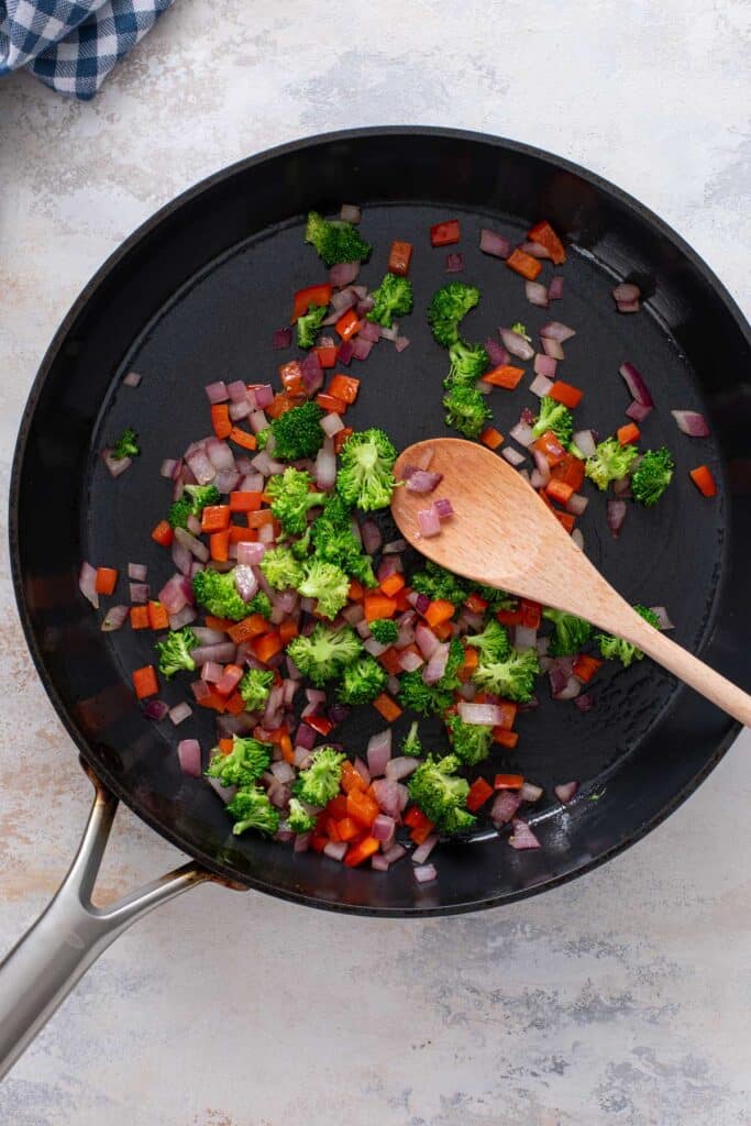 Sautéing red bell pepper, onion and broccoli in a skillet