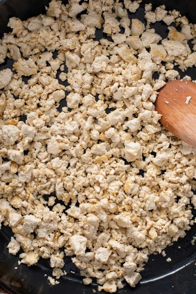 Crumpled tofu developing golden brown edges in a skillet