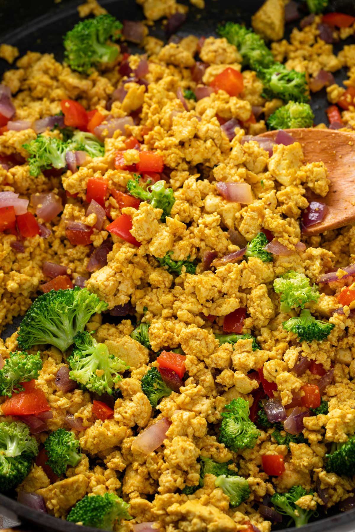 Golden tofu scramble with broccoli, bell pepper and red onion in a skillet