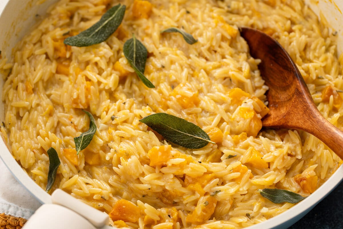 Creamy butternut squash orzo with brown butter and fresh sage in a skillet.