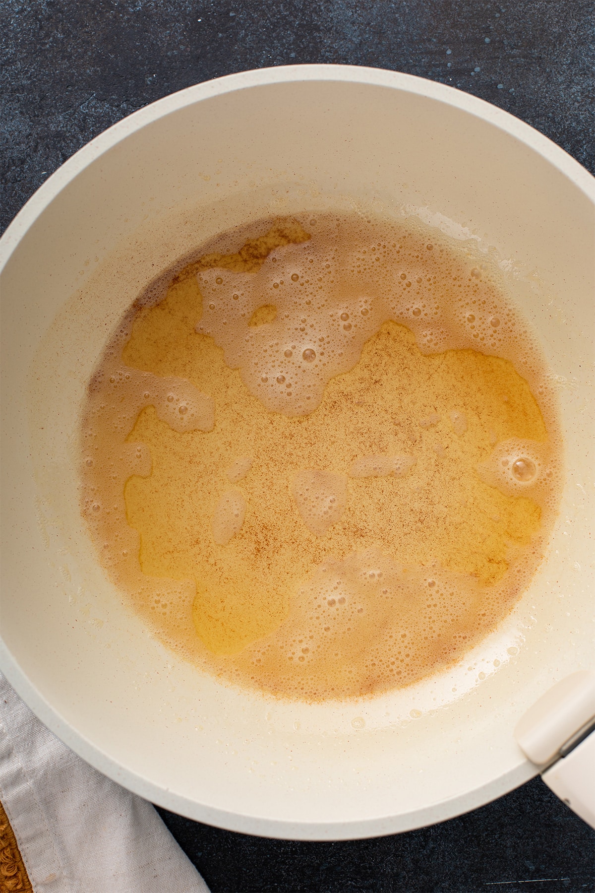 Butter browning and foaming in a white skillet.