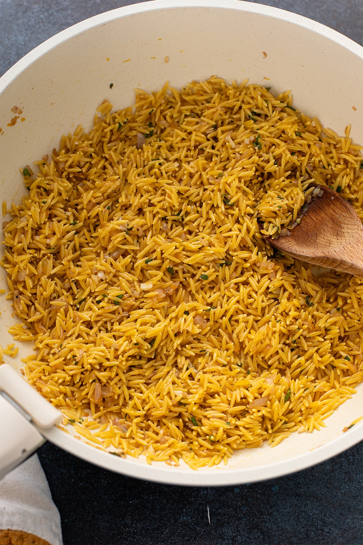 Orzo pasta toasted with brown butter, shallots and fresh herbs in a skillet.