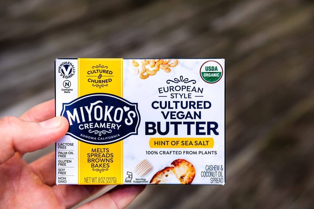 A hand holding a package of Miyoko’s cultured vegan butter.