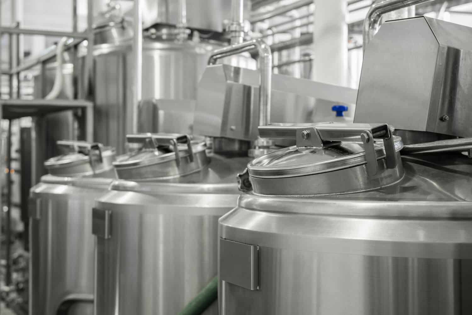 A row of stainless steel milk storage tanks inside a dairy processing plant.