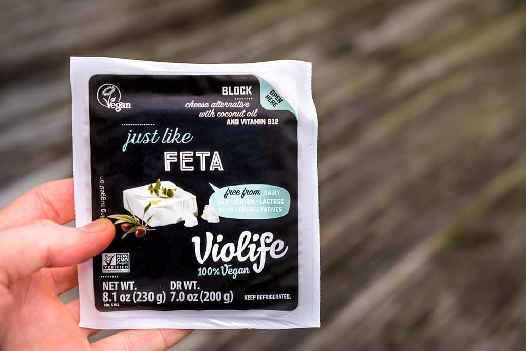 A hand holding a package of Violife plant-based feta.